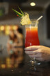 Hand holding a glass of cocktail with two women in the background