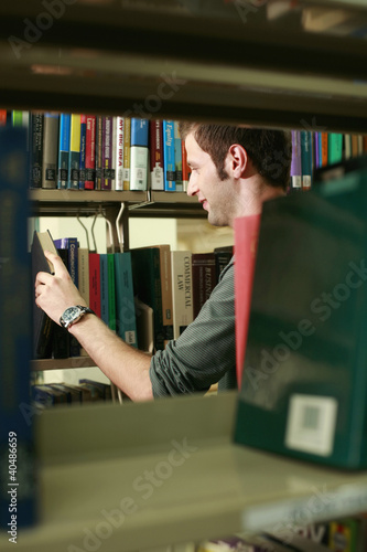 Photo: Man searching for a book in the library Man searching for a book in the library