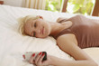 Woman reading text message while lying on bed