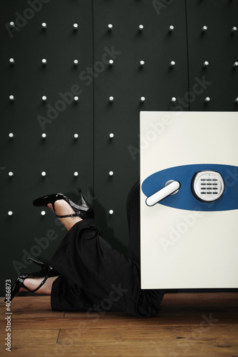 Photo: Businesswoman peering into safe Businesswoman peering into safe