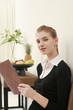 Woman in formal wear holding a book, looking at the camera