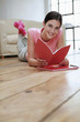 Woman lying forward on the floor reading book
