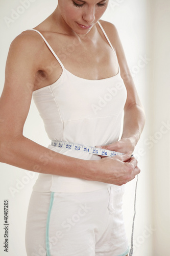 Photo: Woman measuring her waist Woman measuring her waist