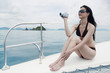 Woman in bikini using video camera on yacht