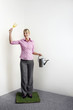 Foto: Businesswoman standing on a patch of grass holding gardening fork and watering can Businesswoman standing on a patch of grass holding gardening fork and watering can