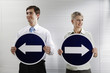Foto: Businessman and businesswoman holding arrow signs showing different directions Businessman and businesswoman holding arrow signs showing different directions