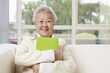 Photo: Senior woman holding book while sitting on the couch Senior woman holding book while sitting on the couch