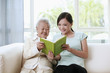 Photo: Senior woman and woman reading book together Senior woman and woman reading book together
