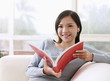 Photo: Woman listening to music on portable MP3 player while reading book Woman listening to music on portable MP3 player while reading book