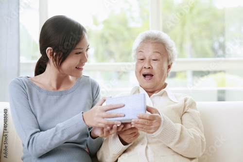 Photo: Woman giving senior woman a box of gift Woman giving senior woman a box of gift