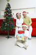 Foto: Boy holding a stack of presents, senior man and senior woman smiling in the background Boy holding a stack of presents, senior man and senior woman smiling in the background