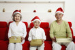 Foto: Boy sitting in between senior man and senior woman, each holding a present Boy sitting in between senior man and senior woman, each holding a present