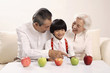 Senior man teaching boy how to count, senior woman smiling while watching