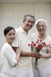 Photo: Senior couple smiling at the camera while holding a bouquet of flowers, woman posing with them Senior couple smiling at the camera while holding a bouquet of flowers, woman posing with them