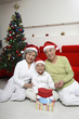 Foto: Boy posing with senior couple under Christmas tree Boy posing with senior couple under Christmas tree