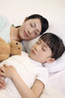 Woman and girl sleeping, girl hugging soft toy