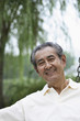 Foto: Senior man smiling at the camera while sitting on a swing Senior man smiling at the camera while sitting on a swing