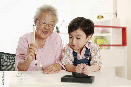 Photo: Boy observing senior woman writing calligraphy Boy observing senior woman writing calligraphy
