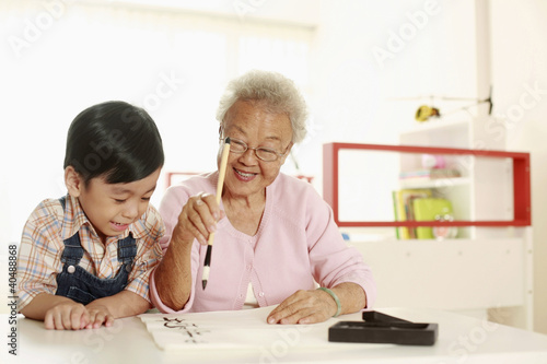 Photo: Boy observing senior woman writing calligraphy Boy observing senior woman writing calligraphy