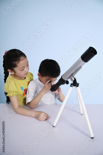 Photo: Boy looking through telescope while girl waits for her turn Boy looking through telescope while girl waits for her turn