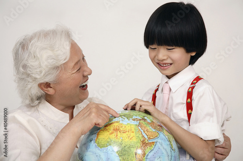 Photo: Boy and senior woman looking at globe Boy and senior woman looking at globe