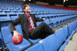 Businessman with football sitting on stadium seat, laughing