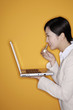 Businesswoman holding laptop and putting on lipstick