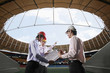Business people discussing blueprints at a stadium