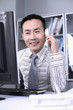 Foto: Businessman working on computer while talking on the phone Businessman working on computer while talking on the phone