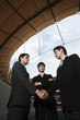 Businessmen shaking hands with another businessman watching in the background