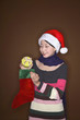 Foto: Woman taking out gift from christmas stocking Woman taking out gift from christmas stocking
