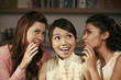 Women whispering into friend's ears