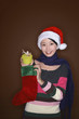 Foto: Woman taking out gift from christmas stocking Woman taking out gift from christmas stocking