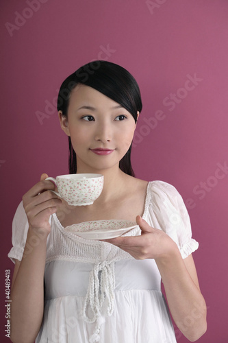 Foto: Woman staring blankly at a space while drinking tea Woman staring blankly at a space while drinking tea