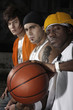 Three men sitting in a row with one of them holding a basketball