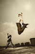 Young woman jumping up high, young man posing in the background