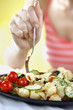 Photo: Woman enjoying a plate of fruit and vegetable pasta salad served with feta cheese and olives on the side Woman enjoying a plate of fruit and vegetable pasta salad served with feta cheese and olives on the side