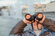 Boy looks through binoculars at the sunset