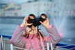 Little girl looks through binoculars at the sunset