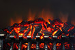 Glowing coals and fire flames in fireplace with metal grating
