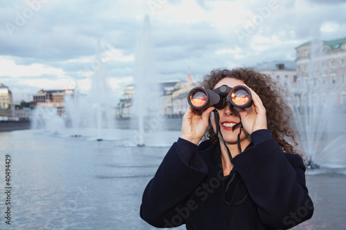 Photo: Young woman looks through binoculars at the sunset Young woman looks through binoculars at the sunset