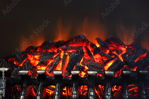 Photo: Glowing coals and fire flames in fireplace with metal grating Glowing coals and fire flames in fireplace with metal grating
