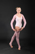 Girl gymnast wearing in pink suit took graceful pose in studio