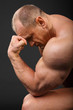 Undressed tanned bodybuilder leaned his forehead on fist