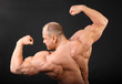 Undressed tanned bodybuilder shows muscles of arms and back