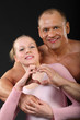 sunburnt bodybuilder hugs with girl and represents heart
