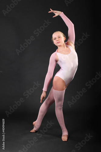 Photo: Girl gymnast wearing in pink suit took graceful pose in studio Girl gymnast wearing in pink suit took graceful pose in studio