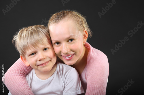 Photo: Little blond brother and beautiful sister embrace on black Little blond brother and beautiful sister embrace on black