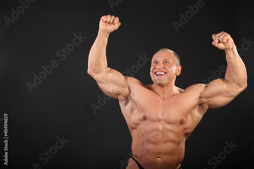 Photo: Undressed tanned happy bodybuilder raises his fists up Undressed tanned happy bodybuilder raises his fists up