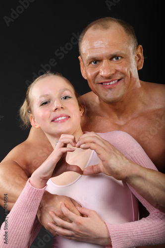 Photo: sunburnt bodybuilder hugs with girl and represents heart sunburnt bodybuilder hugs with girl and represents heart